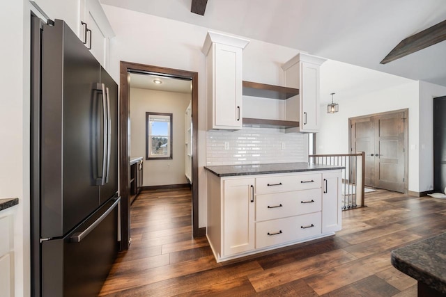 kitchen with stainless steel fridge, white cabinetry, dark hardwood / wood-style floors, decorative backsplash, and dark stone counters