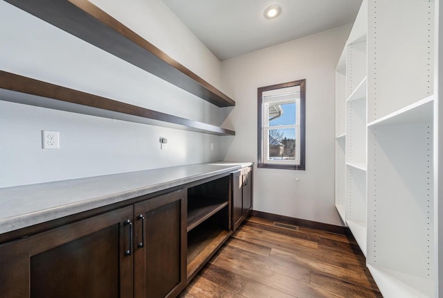 bar with dark brown cabinets and dark hardwood / wood-style floors