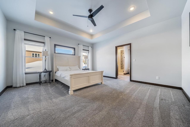 unfurnished bedroom with ceiling fan, carpet flooring, and a raised ceiling