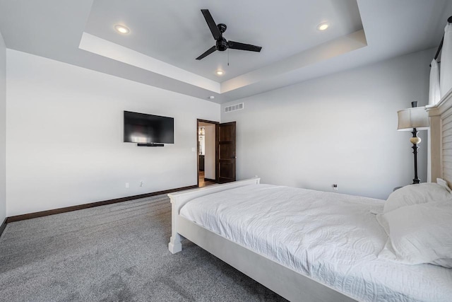 bedroom with a raised ceiling, ceiling fan, and carpet flooring