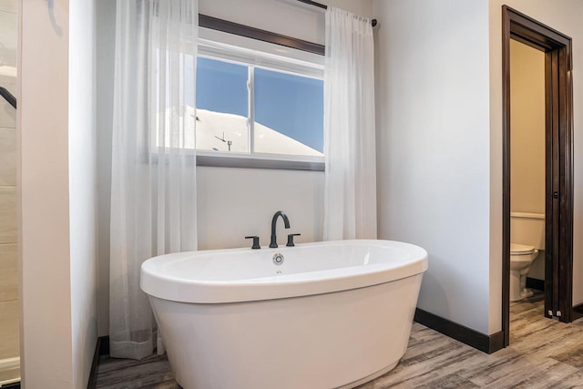 bathroom with a bath, hardwood / wood-style floors, and toilet