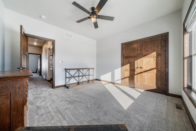 empty room with ceiling fan and dark colored carpet