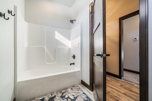 bathroom featuring hardwood / wood-style flooring and washtub / shower combination