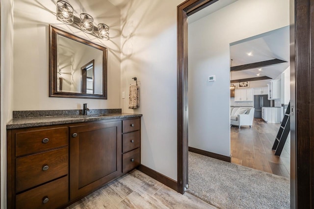 bathroom with beamed ceiling, vanity, and hardwood / wood-style flooring