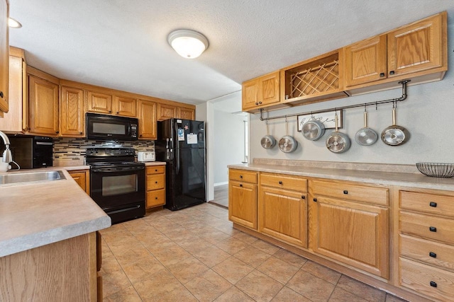 kitchen featuring sink, tasteful backsplash, a textured ceiling, light tile patterned floors, and black appliances