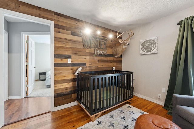 bedroom featuring hardwood / wood-style floors, a textured ceiling, and wood walls