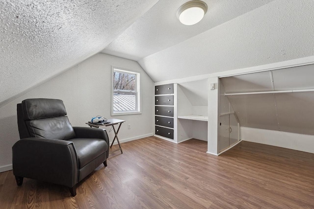 sitting room featuring lofted ceiling, hardwood / wood-style floors, and a textured ceiling