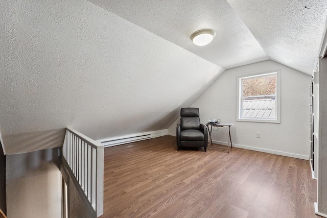 unfurnished room featuring a textured ceiling, a baseboard radiator, wood-type flooring, and vaulted ceiling