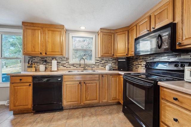 kitchen with sink, decorative backsplash, a wealth of natural light, and black appliances