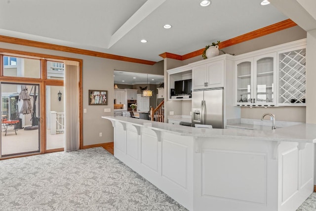 kitchen with stainless steel built in refrigerator, crown molding, hanging light fixtures, kitchen peninsula, and white cabinets