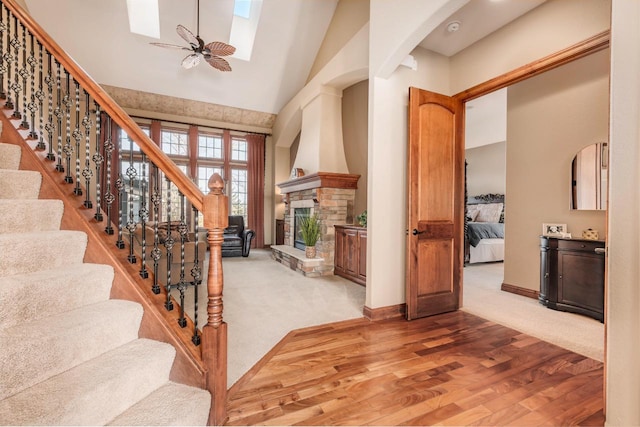 living room featuring ceiling fan, high vaulted ceiling, light colored carpet, and a fireplace