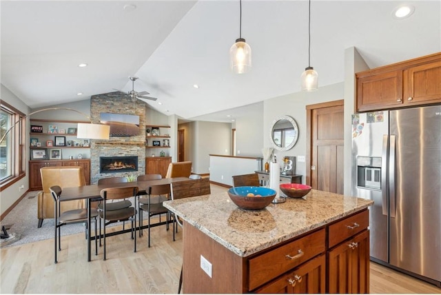 1787 Otter Way, New Richmond, WI 54017 - kitchen with stainless steel fridge, a stone fireplace, a center island, decorative light fixtures, and vaulted ceiling