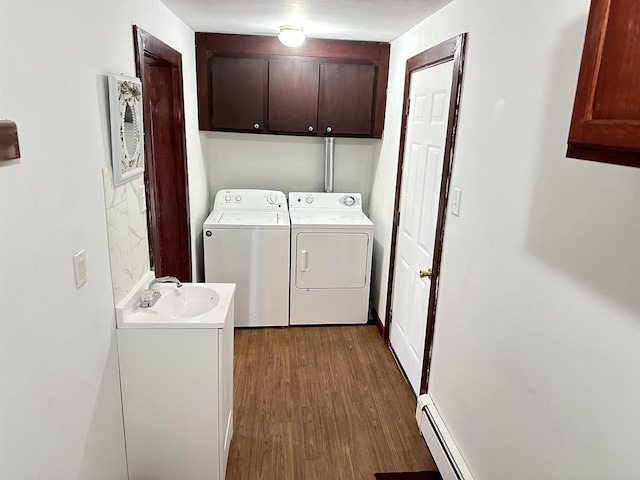 clothes washing area featuring dark hardwood / wood-style floors, sink, cabinets, independent washer and dryer, and baseboard heating