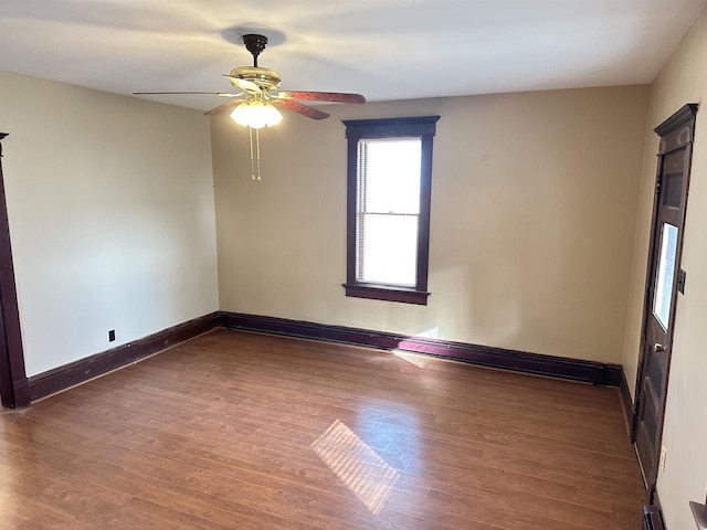 empty room with ceiling fan, dark hardwood / wood-style floors, and a baseboard heating unit