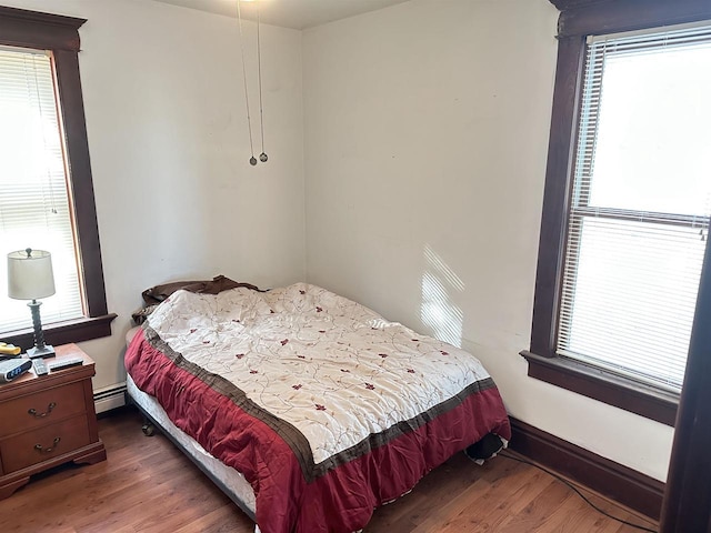 bedroom with dark hardwood / wood-style floors and baseboard heating