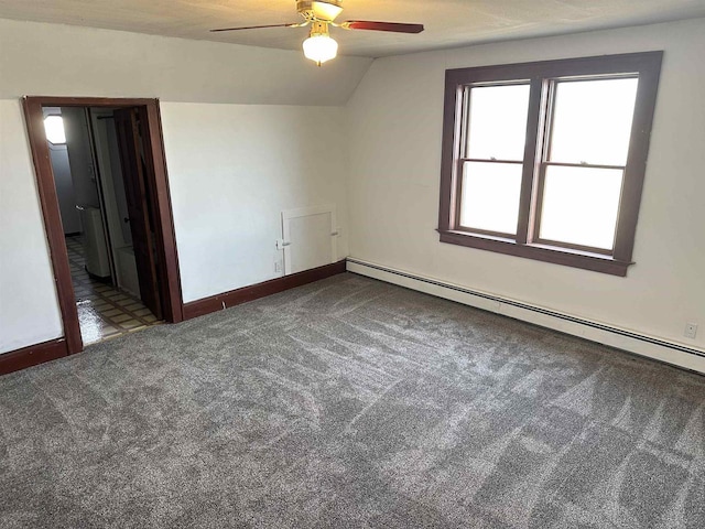 interior space with baseboard heating, ceiling fan, vaulted ceiling, and dark colored carpet