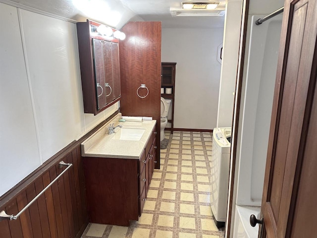 bathroom featuring vanity, vaulted ceiling, independent washer and dryer, and toilet