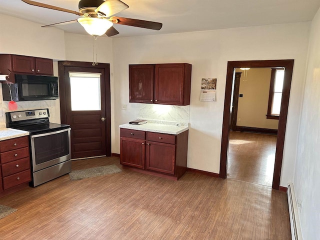 kitchen featuring electric stove, light hardwood / wood-style flooring, ceiling fan, baseboard heating, and backsplash