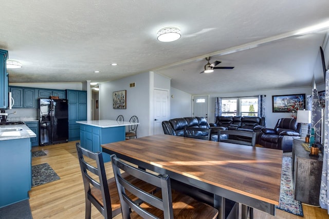 dining space with ceiling fan, sink, light hardwood / wood-style floors, and a textured ceiling