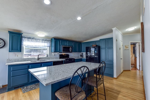 kitchen featuring sink, a breakfast bar area, a kitchen island, black appliances, and blue cabinets