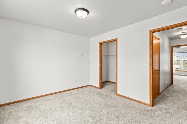 unfurnished bedroom featuring a closet, a spacious closet, and light carpet