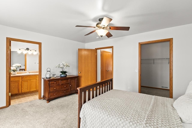 carpeted bedroom with sink, ceiling fan, ensuite bathroom, a spacious closet, and a closet