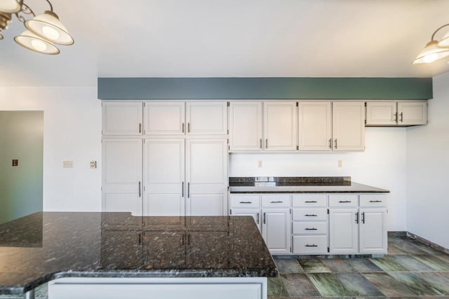 kitchen featuring white cabinetry and dark stone countertops