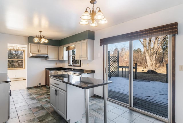 kitchen featuring sink, a chandelier, baseboard heating, a kitchen breakfast bar, and a kitchen island