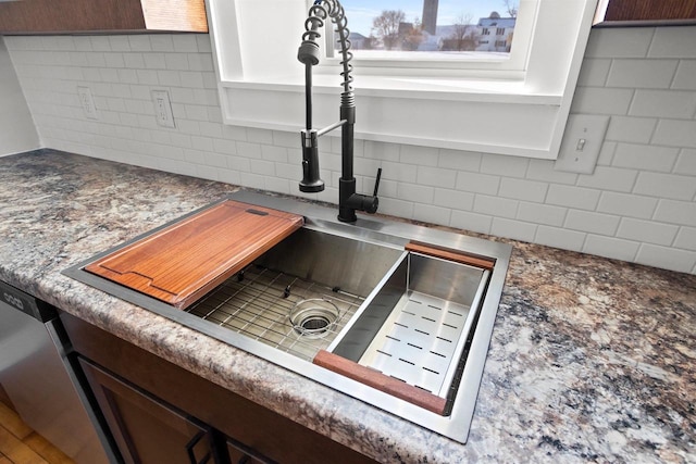 interior details featuring tasteful backsplash, white cabinetry, sink, and stainless steel dishwasher