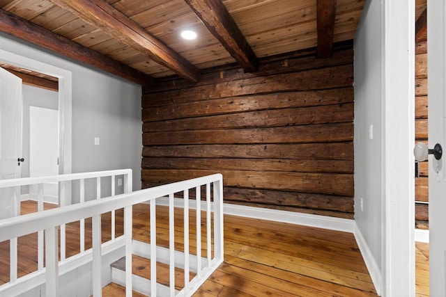 hallway featuring beam ceiling, wood ceiling, wood-type flooring, and wooden walls