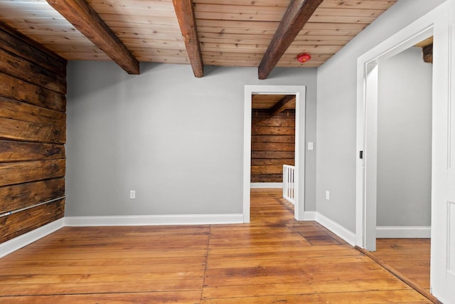 spare room featuring beam ceiling, wood ceiling, and light hardwood / wood-style flooring