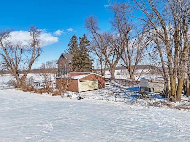 yard layered in snow with a garage and an outbuilding