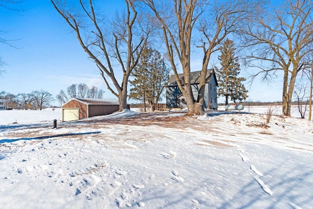 snowy yard featuring a garage and an outdoor structure