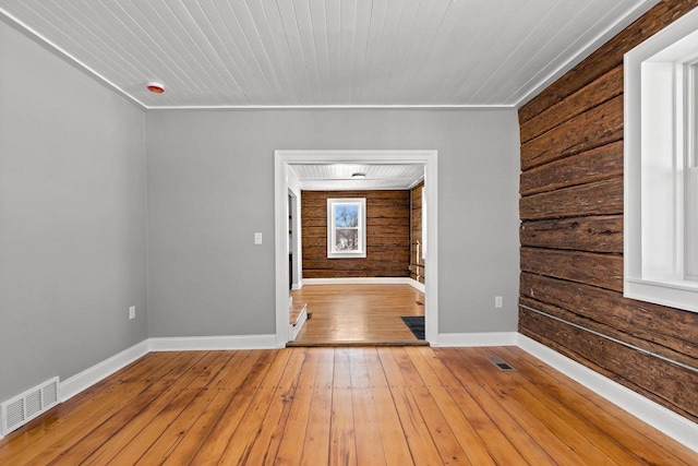 unfurnished room with wooden ceiling, wooden walls, and light wood-type flooring