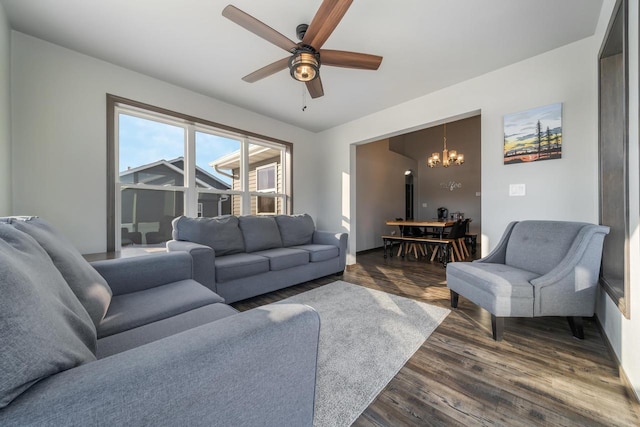 living room with ceiling fan with notable chandelier and dark wood-type flooring