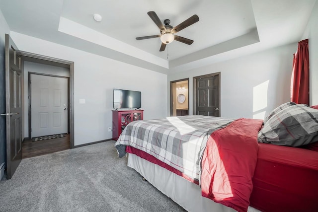 carpeted bedroom with a tray ceiling, ceiling fan, and ensuite bathroom