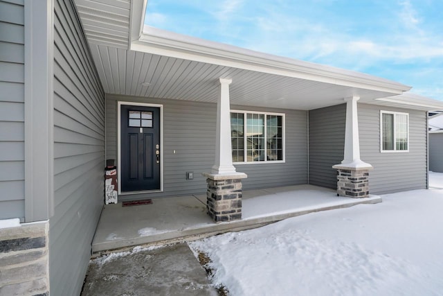 snow covered property entrance featuring a porch