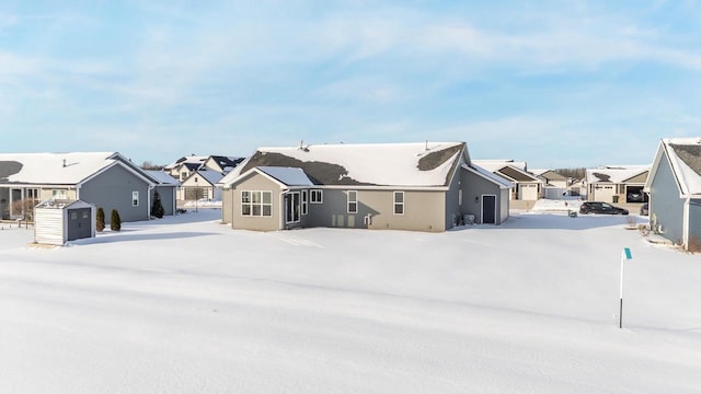 snow covered rear of property with a shed