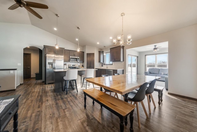 dining room featuring sink, ceiling fan with notable chandelier, high vaulted ceiling, and dark hardwood / wood-style floors