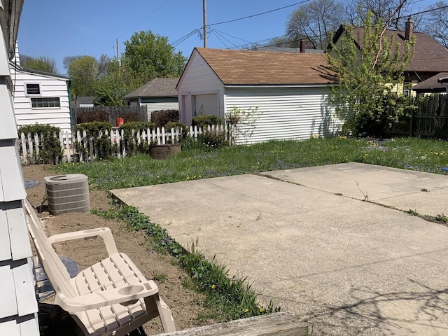 view of yard featuring fence, central air condition unit, and an outbuilding