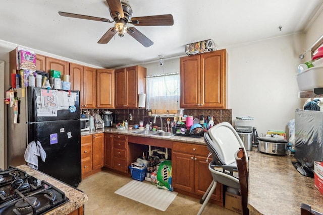 kitchen featuring black appliances, a sink, ceiling fan, brown cabinets, and crown molding