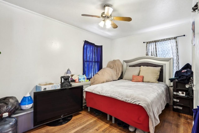 bedroom featuring wood finished floors, a ceiling fan, and ornamental molding
