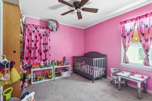 carpeted bedroom with crown molding, ceiling fan, a crib, and baseboards