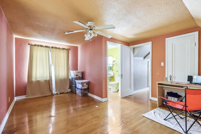 office featuring a textured ceiling, ceiling fan, baseboards, and wood finished floors