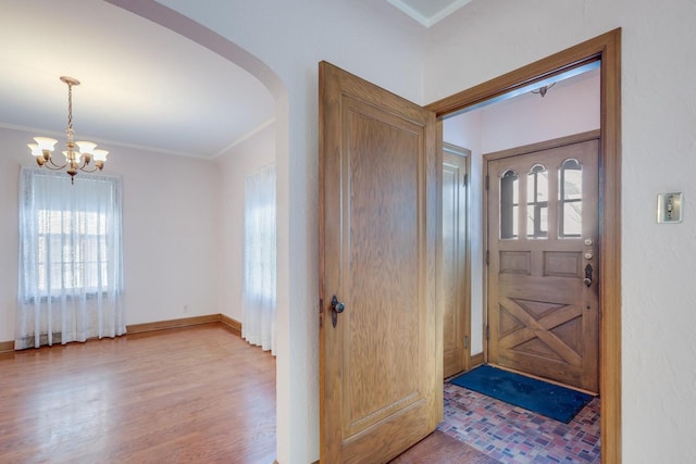 foyer featuring hardwood / wood-style flooring, ornamental molding, and a chandelier