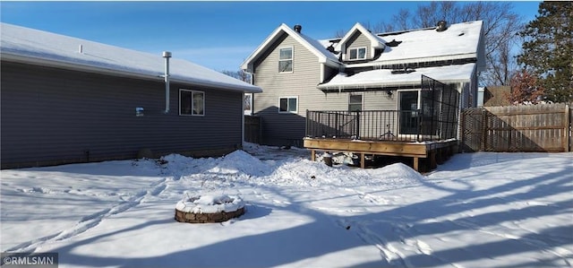 snow covered house with a wooden deck