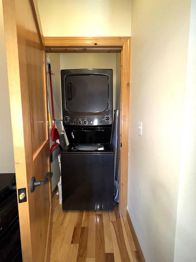 laundry room featuring hardwood / wood-style flooring and stacked washing maching and dryer