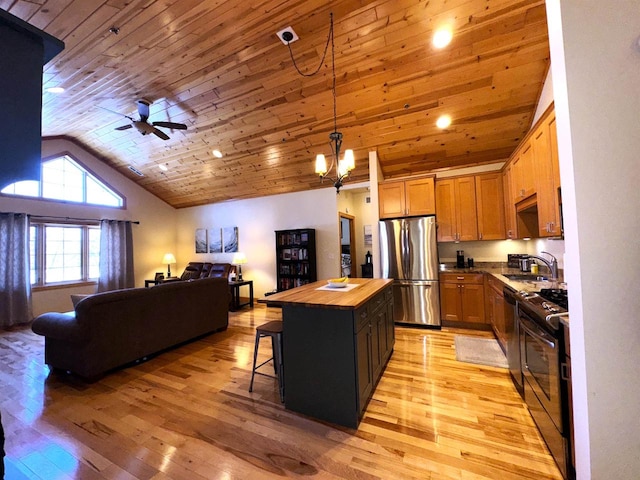 kitchen with pendant lighting, wooden counters, appliances with stainless steel finishes, a kitchen breakfast bar, and a kitchen island