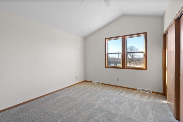 unfurnished bedroom featuring ceiling fan, a closet, vaulted ceiling, and light carpet