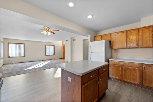 kitchen featuring white refrigerator, wood-type flooring, a center island, and ceiling fan